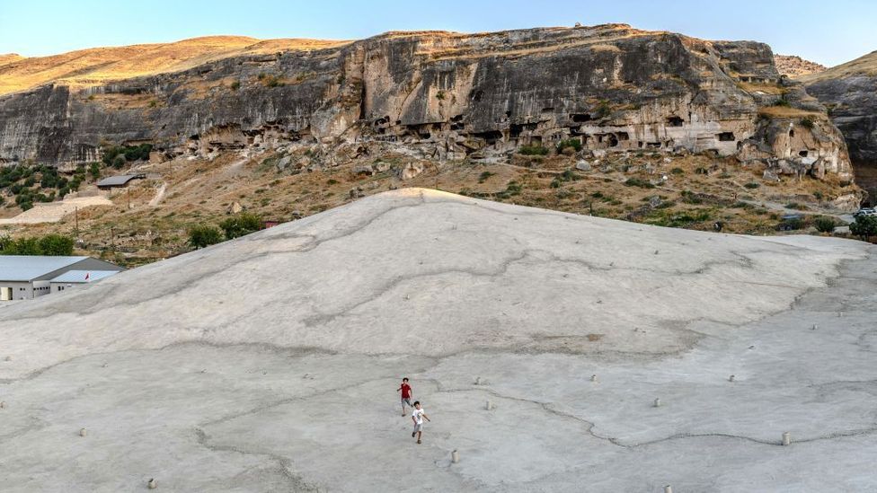 Children play on a concrete plain created to protect a mosque in Hasankeyf, Turkey from the deliberate flooding of a reservoir (Credit: Bulent Kilic/Getty Images)