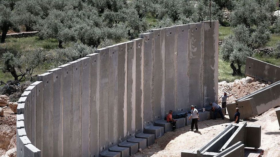 Concrete builds, but it can also divide. A controversial barrier in the town of Beit Jala in the West Bank (Credit: Thomas Coex/Getty Images)