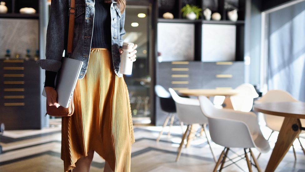 Woman carrying coffee and laptop heading to work