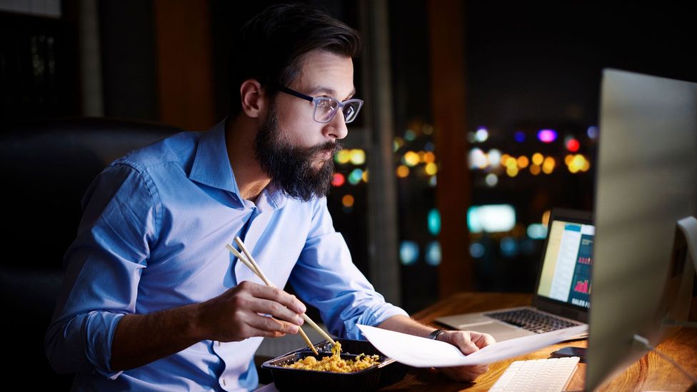 Man eating noodles at his desk