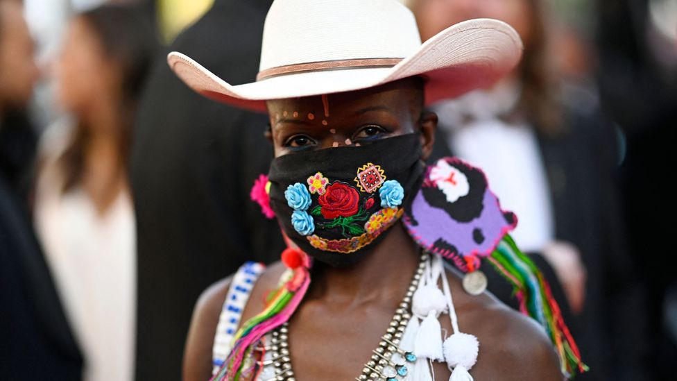 Female guest in cowboy hat and mask (Credit: Christopeh Simon/AFP/Getty Images)