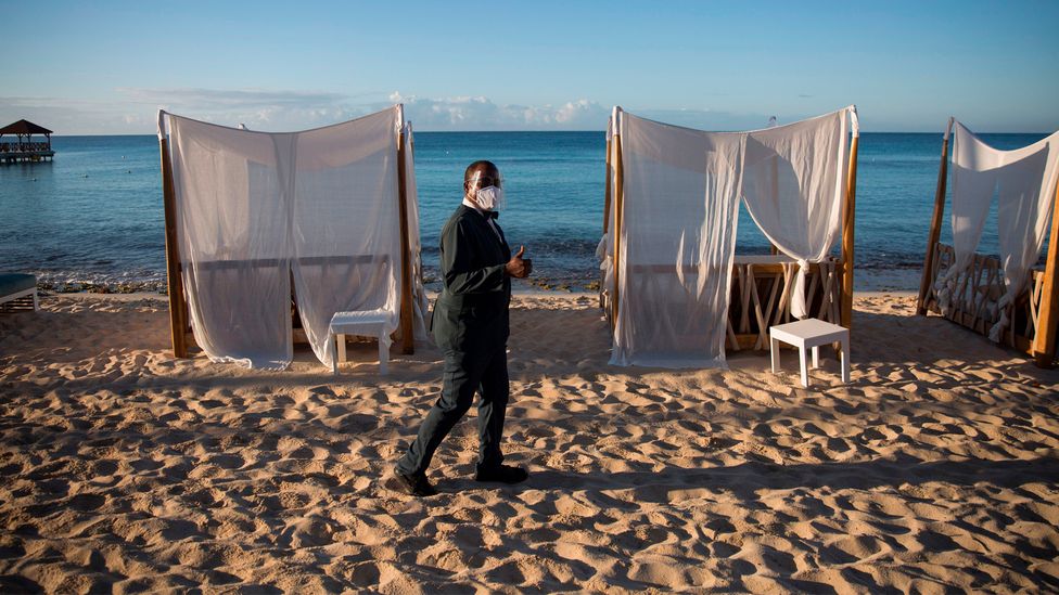 Masked worker in deserted beach resort (Credit: Erika Santelices/AFP/Getty Images)
