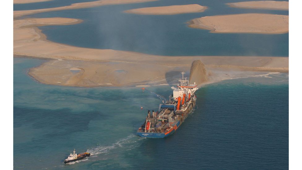A ship in the Persian Gulf pumping tonnes of sediment into the sea, gradually growing an island (Credit: Getty)