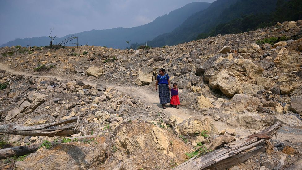 An indigenous woman and child walk by a landslide that destroyed the Guatemalan village of Queca after heavy rains from a hurricane in 2021 (Credit: J.ORDONEZ/Getty)