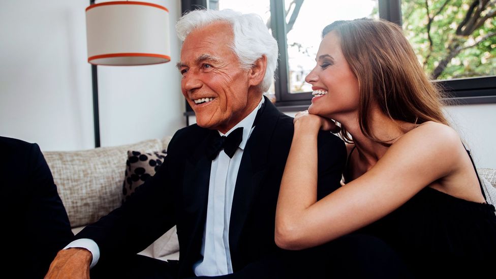 An older man and a younger woman, looking happy