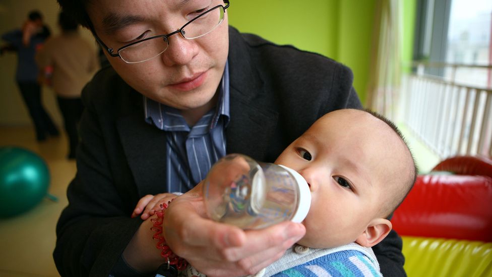 A dad bottle-feeds his son in a pre-school class in Beijing (Credit: Gou Yige/AFP via Getty Images)