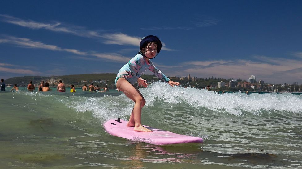 A girl surfs a wave at Freshwater Beach in Sydney, Australia (Credit: Lee Hulsman/Getty Images)