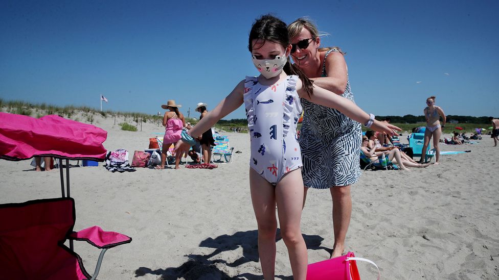 A beachgoer helps her daughter with sunscreen on Good Harbor Beach in Gloucester, Massachusetts (Credit: Craig F. Walker/The Boston Globe via Getty Images)