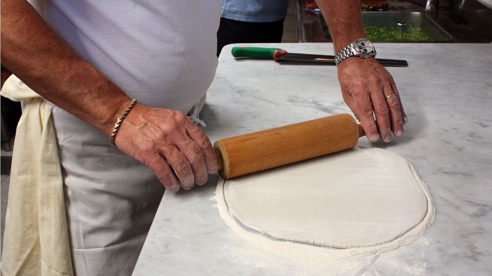 Roberto Scínetti rolls pizzoccheri dough into thin disks on a marble countertop (Credit: Lorenzo Caglioni)