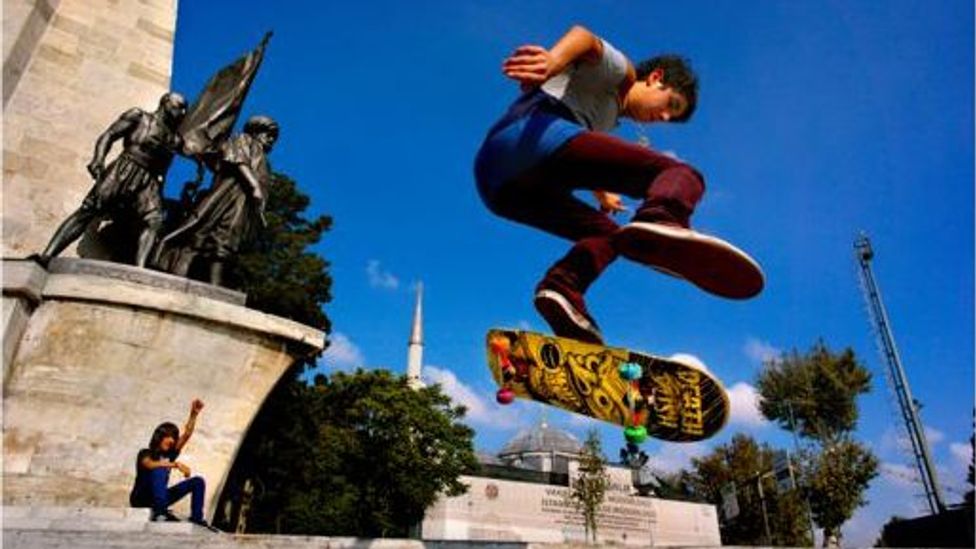 A boy leaps through the air on a skateboard