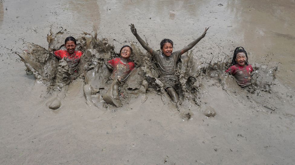A group of children enjoy a mud bath on Nepal's National Paddy Day, which marks the start of the rice planting season (Credit: Getty Images)