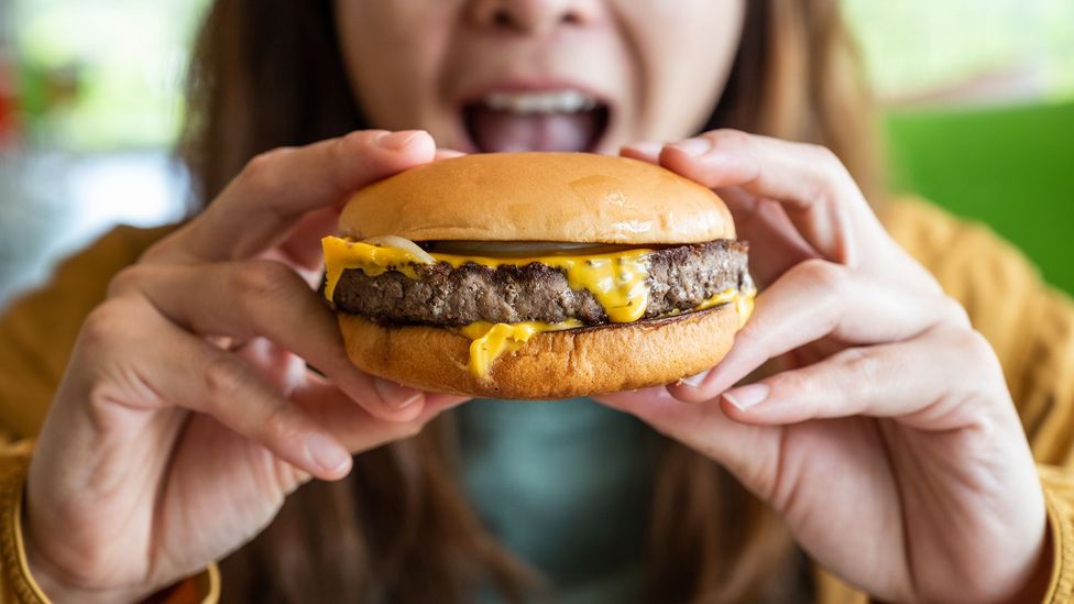 Woman eating burger (Credit: Boy_Anupong/Getty Images)
