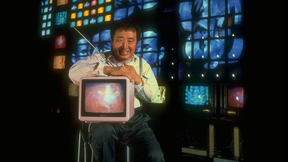 US-Korean artist Nam June Paik, shown here with his 1989 video sculpture Fin de Siecle II, was an early adopter of video art (Credit: Mario Ruiz/ Getty)