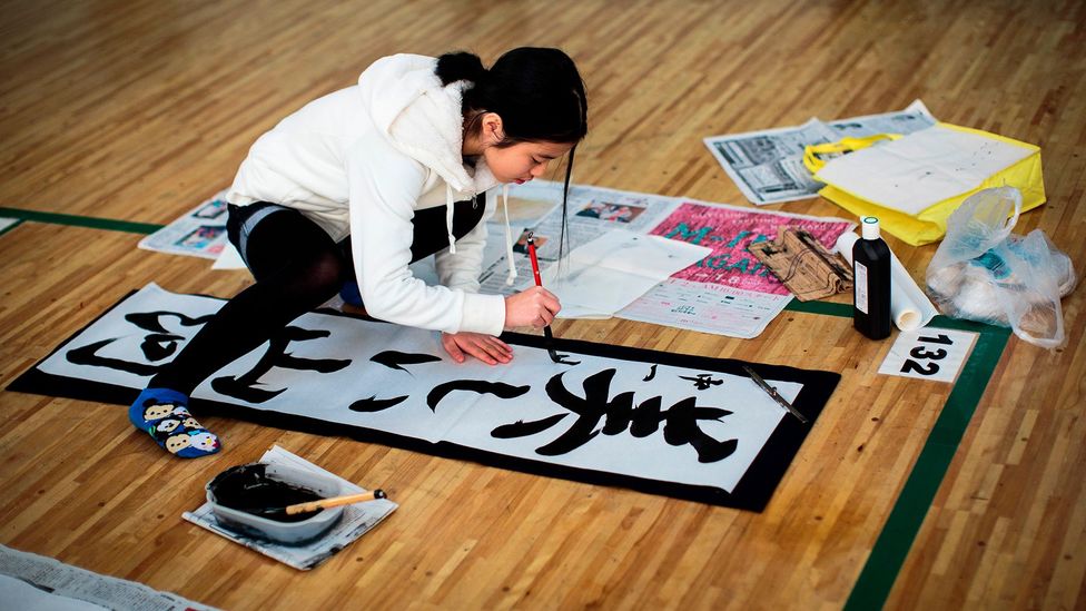 A participant writes Japanese calligraphy during a New Year calligraphy contest in Tokyo (Credit: Getty Images)