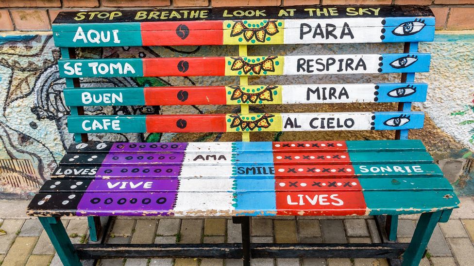 A bench in Bogota, Colombia, with Spanish and English messages inviting passers-by to take a coffee break (Credit: Getty Images)