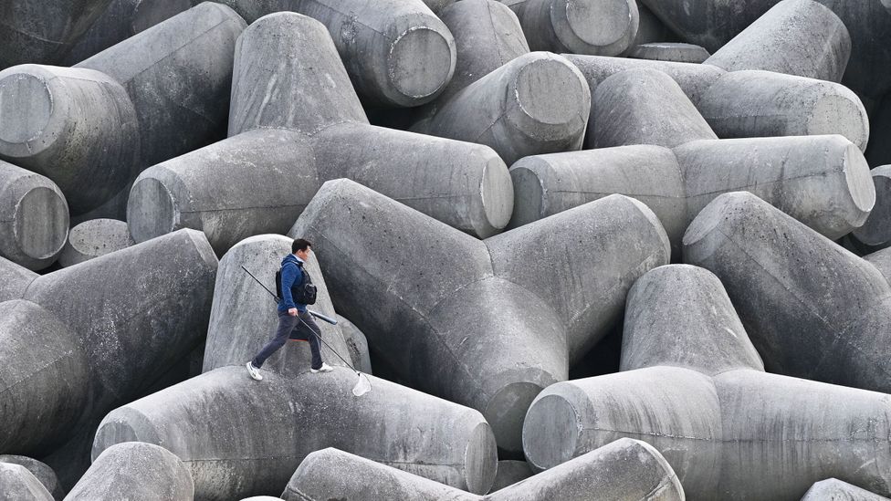 A man walks over a concrete sea defence (Credit: Getty Images)