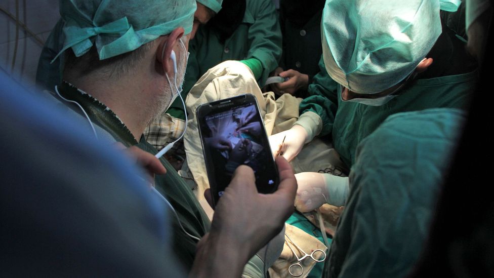 A surgeon conducts a consultation using a mobile phone (Credit: Getty Images)