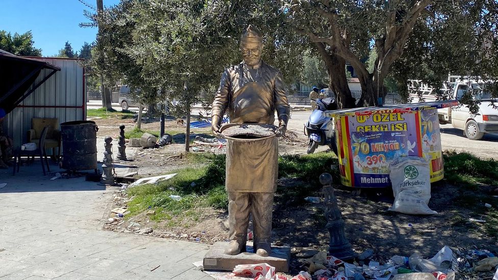 A statue of a künefe master stands alone amid Hatay's post-earthquake destruction (Credit: Gonca Tokyol)