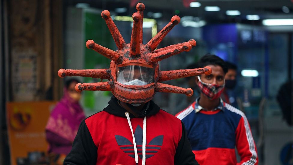 A man wearing a helmet shaped like a virus (Credit: Getty Images)