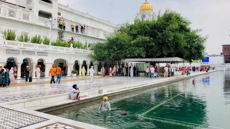 Sikhs all over the world do seva, such as cleaning the Golden Temple's holy pool (Credit: Raphael Reichel)