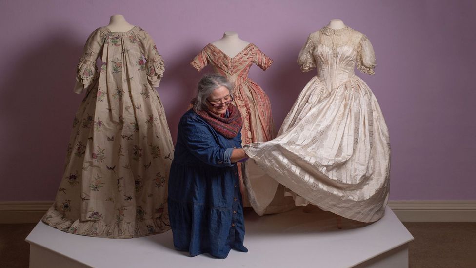 Curator Shelley Tobin with 18th and 19th-Century gowns that have been created by re-purposing precious silk fabrics (Credit: National Trust/ Steve Haywood)
