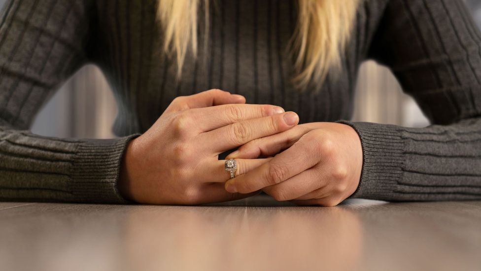 Woman pulling off her wedding ring at table