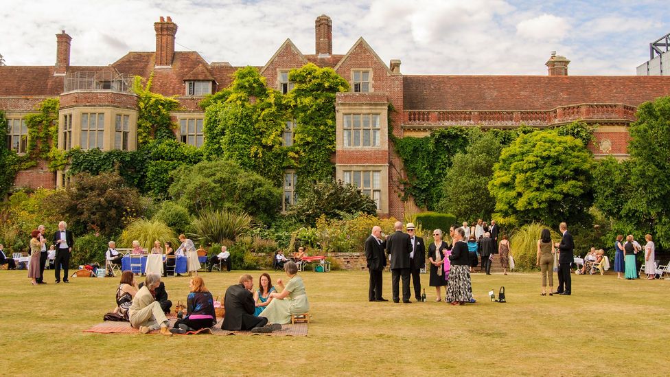 View of Glyndebourne Opera House exterior and grounds with opera goers gathered outside