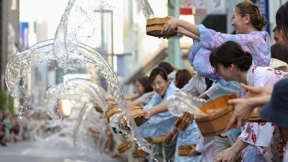 People in traditional dress splash water during the Uchimizu water sprinkling event