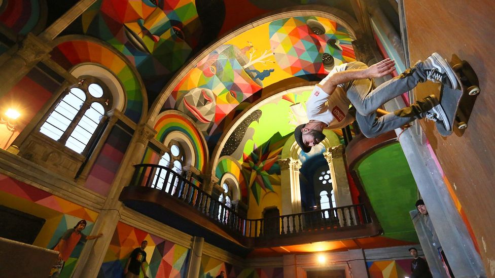 Skateboarder skates on ramp in brightly coloured church interior