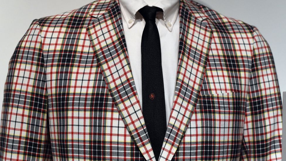 A man's sports jacket in Madras check worn with button-down shirt and tie