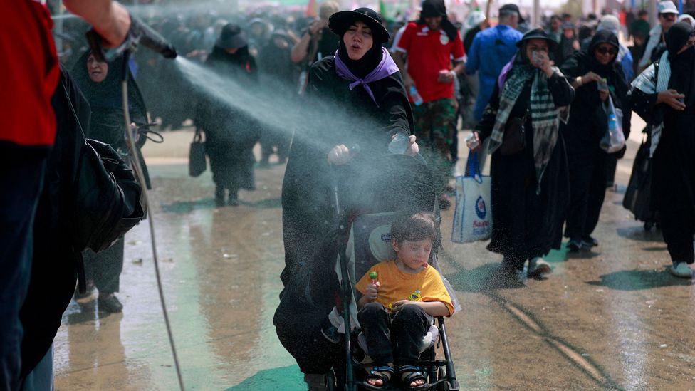 A woman and child are sprayed with water to keep cool