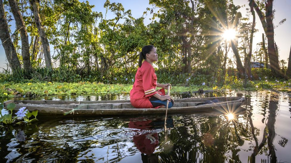 A woman steers her traditional boat through a lake in the Philippines (Credit: Gab Mejia)