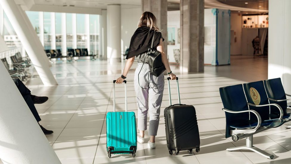 Woman dragging suitcases behind her in airport