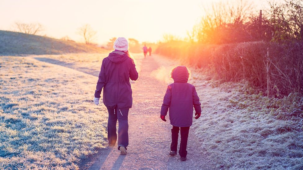 Two people out for a winter walk with frost on the ground (Credit: Getty Images)