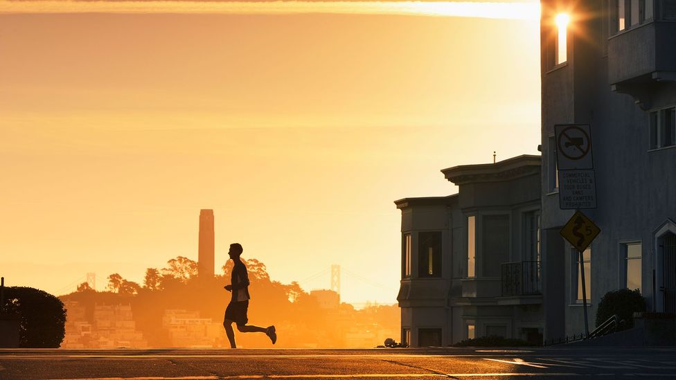A runner crosses a street at sunrise (Credit: Getty Images)