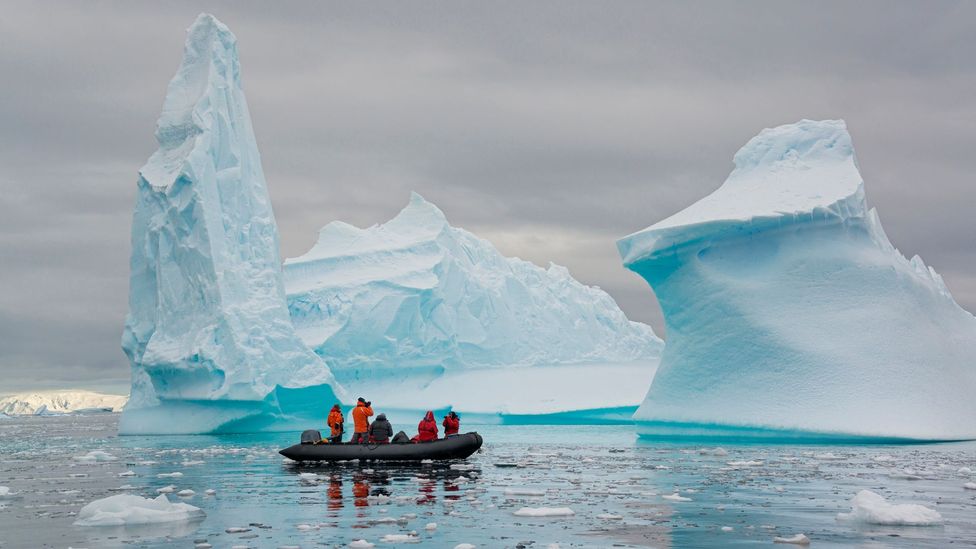 People in a zodiac in front of two icebergs on the Antarctic Peninsula