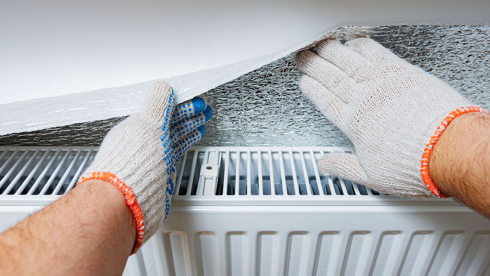 Someone applies reflective foil behind their radiator