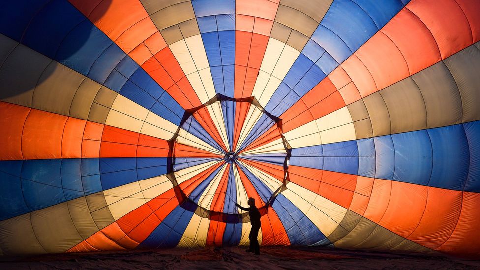 A person adjusts some lines inside a hot air balloon before take off on August 04, 2021 in Bristol, England. "Fiesta Fortnight" takes place until Sunday 15th August 2021 with hundreds of hot-air balloons taking off from multiple locations across the city, filling the sky with not only classic hot air balloons, but some special shapes and characters including Stuart the Minion. (Photo by Finnbarr Webster/Getty Images)