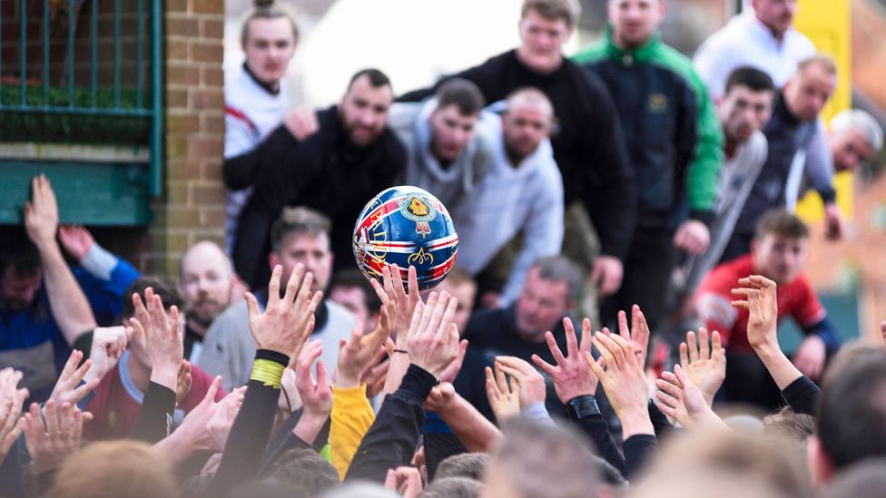 People reaching for the ball at the Royal Shrovetide Street Football in Ashbourne