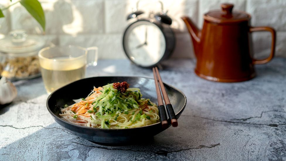 A plate of Chinese homemade noodles and a clock (Credit: Getty Images)