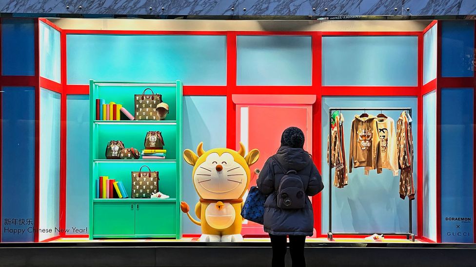 A pedestrian walks past a Doraemon figure on display in the window of a Guccio Gucci Spa