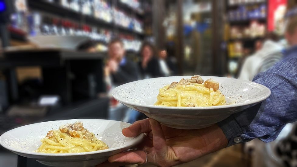 A waiter holds two plates of carbonara in Roscioli's Salumeria restaurant (Credit: Andrea Carlo Martinez)