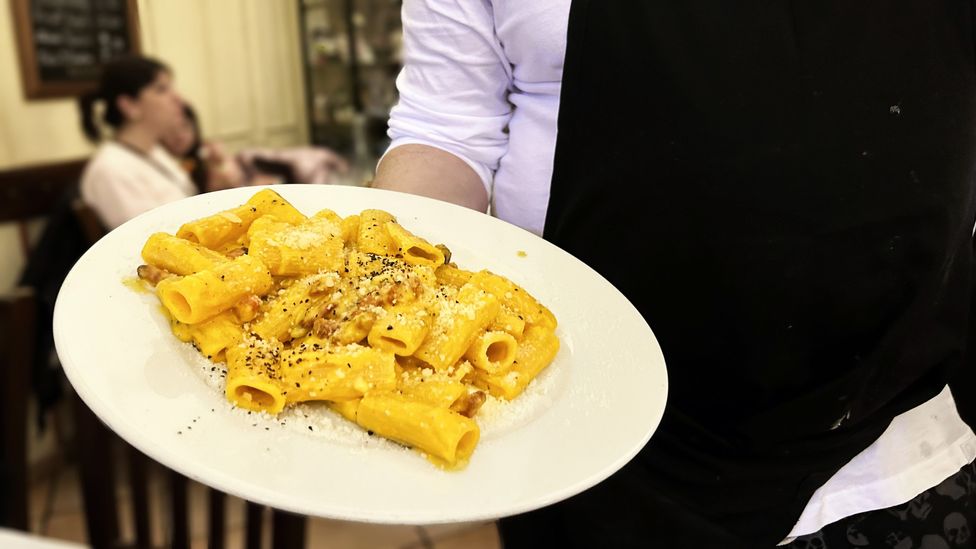 Chef Teodoro Filippini holds a plate of carbonara — his restaurant's signature dish (Credit: Andrea Carlo Martinez)