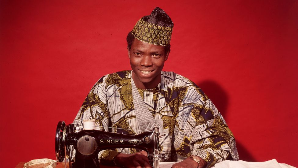 Tailor in traditional Nigerian outfit with sewing machine