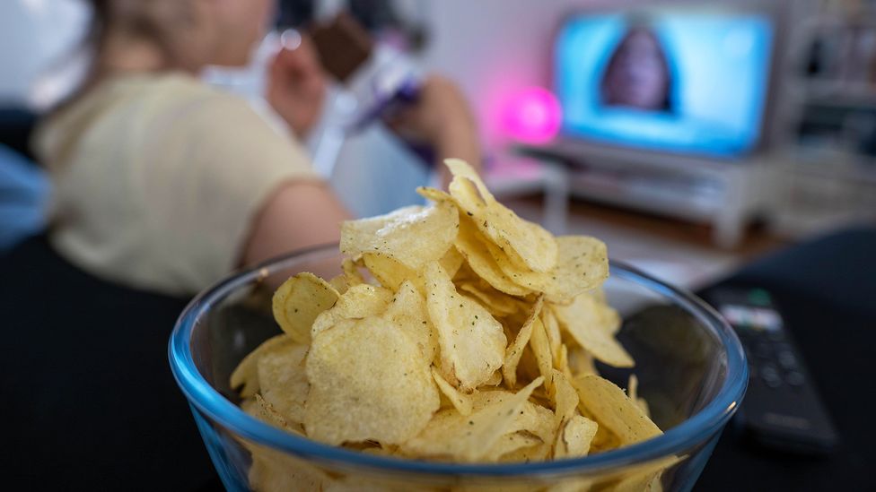 Eating while distracted by a TV show may make us more likely to eat more than we should, studies suggest (Credit: Alamy)