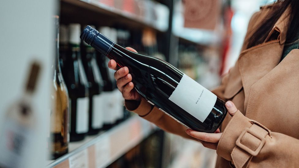 A woman holds a bottle of red wine (Credit: Getty Images)