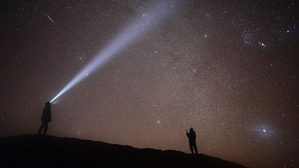 Two people look up at a meteor streaking across a star speckled sky (Credit: Getty Images)
