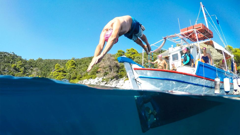 Someone diving head first off a boat into water (Credit: SwimTrek/ Andrew Cole)