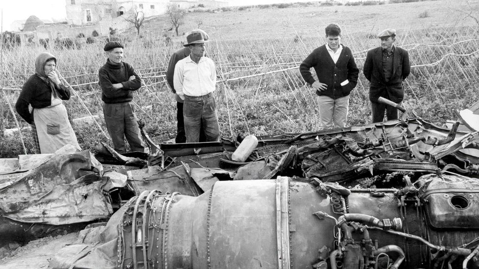 A small group of people stand around the remnants of a fallen bomb in a Spanish village (Credit: Alamy)