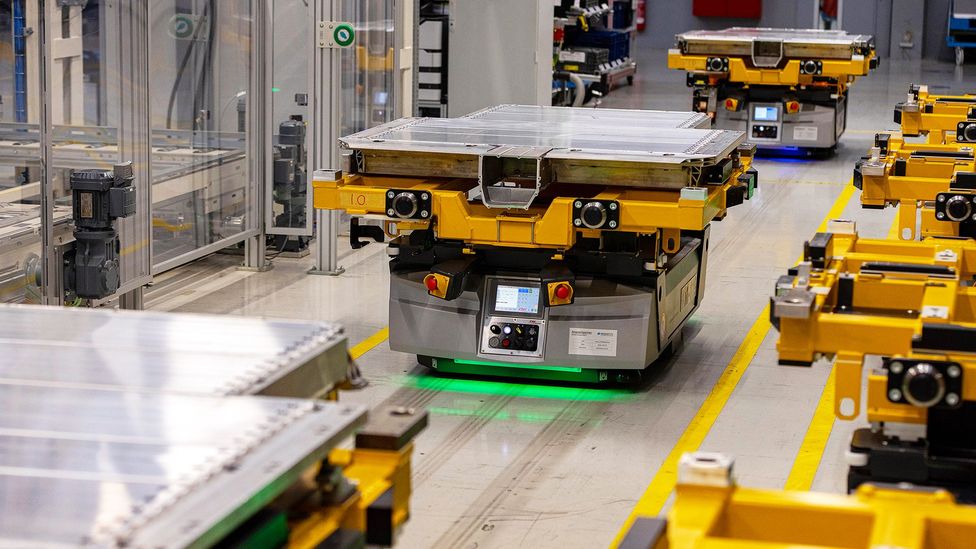 Car batteries are transported through a factory on flatbed robots (Credit: Getty Images)